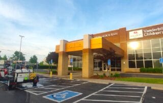 Professional technician pressure washing stained concrete at a Franklin commercial property entrance
